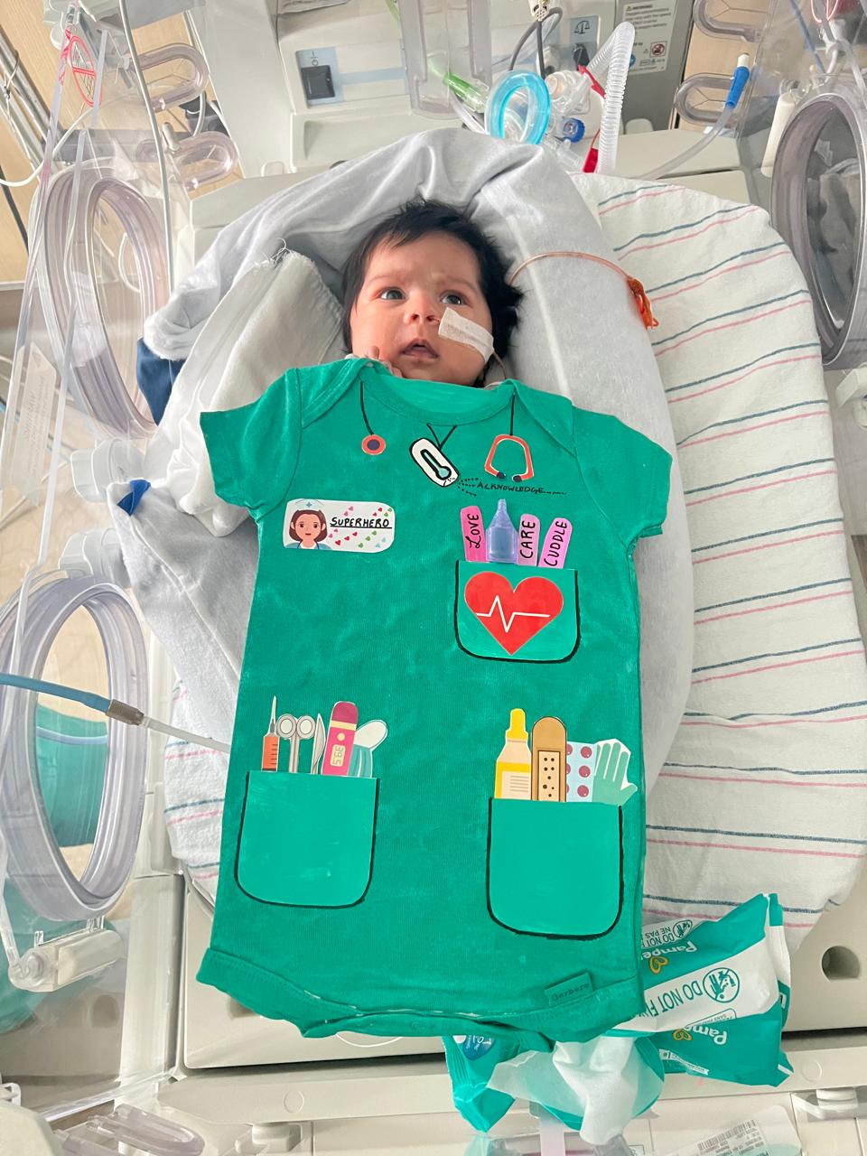 a baby with a onesie draped on top of her