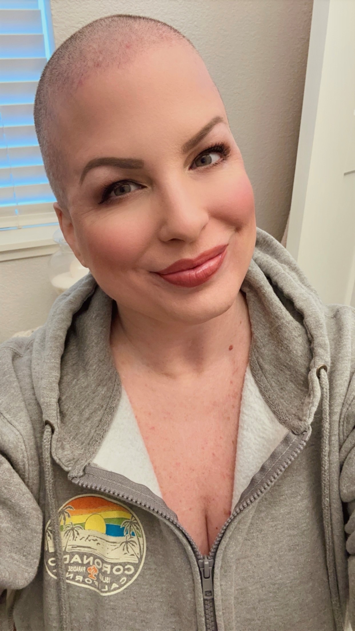 A caucasian woman in a sweater shirt who is bald