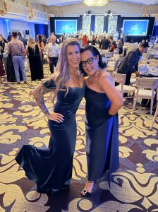 Two women wearing long blue gowns posing next to each other.