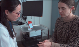 Photo of doctor treating a patient while Abridge app is used in the background