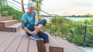 Woman holding ankle on steps after exercise
