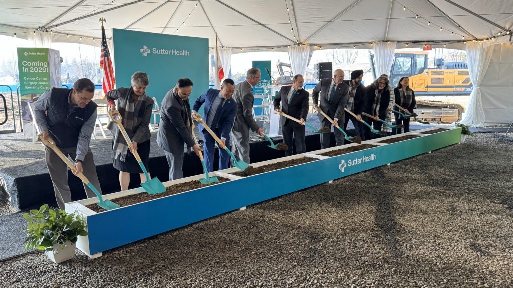 Men and women gather for a groundbreaking ceremony with shovels and dirt