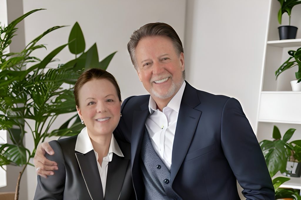 Couple in business attire posing together in a living room