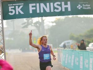 SF Half Marathon 5K first place winner runs through the finish line.