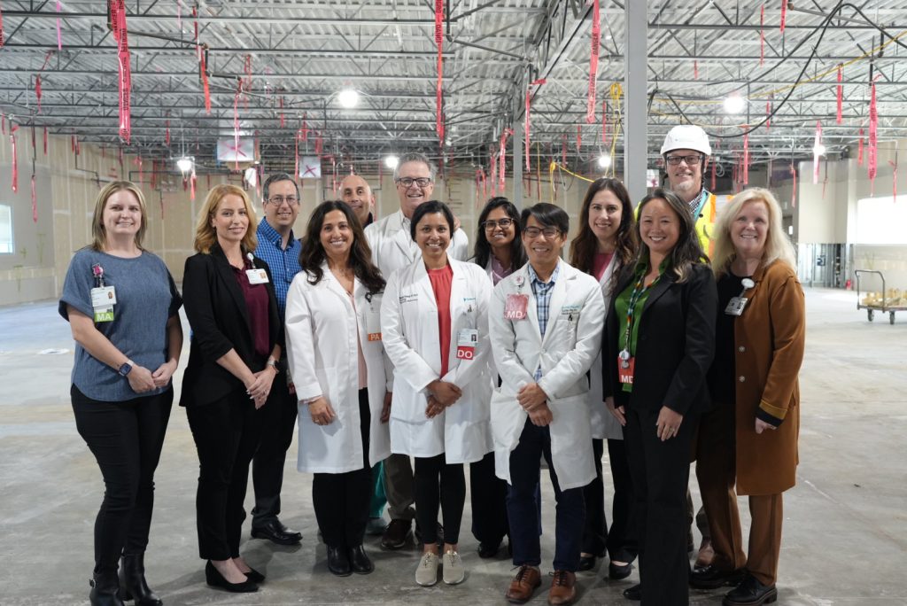 A cardiology team stands in a construction space that will eventually become their office