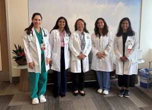 Five female cardiologists stand in their white coats