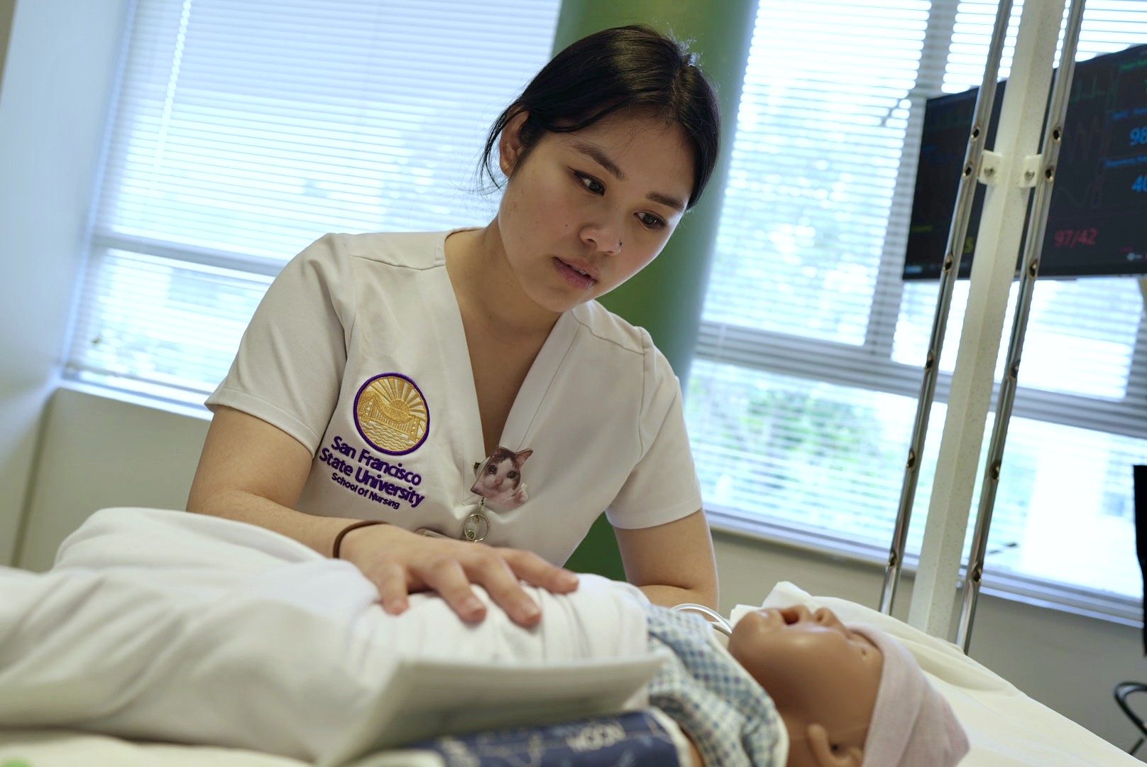 A student nurse places her hand on the chest of a high-fidelity infant training manikin