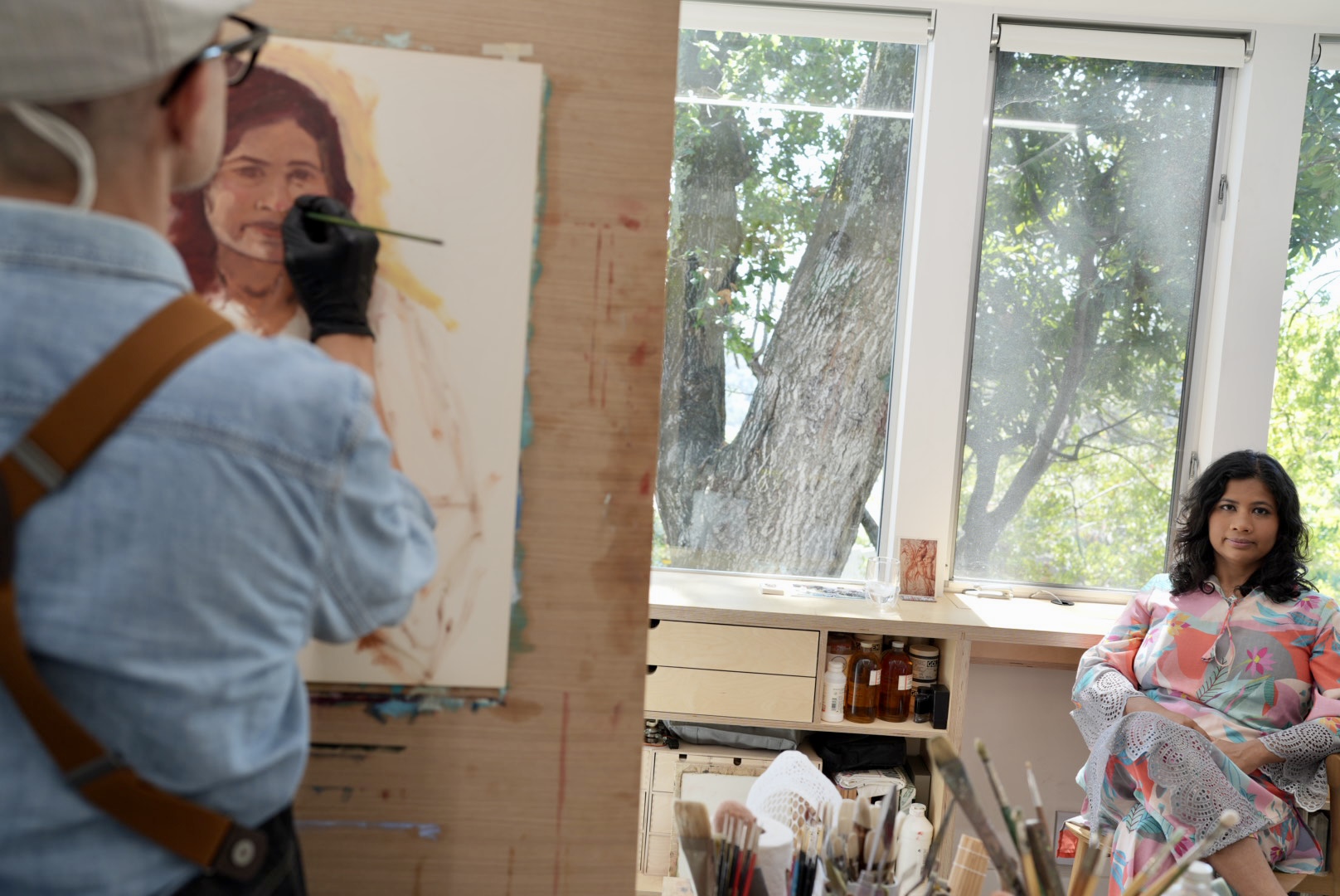 An artist paints a portrait in a brightly lit studio