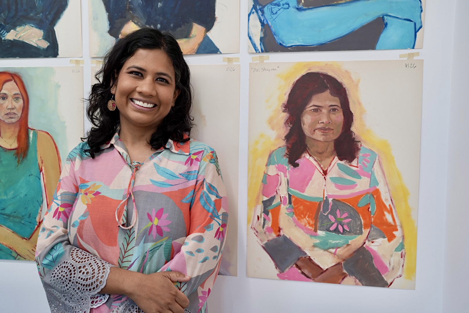 A woman stands next to her painted portrait 