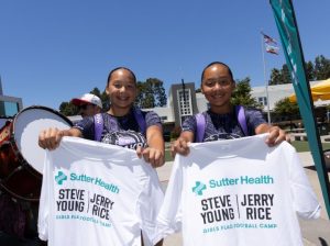 Two girls holding up flag football tee shirts