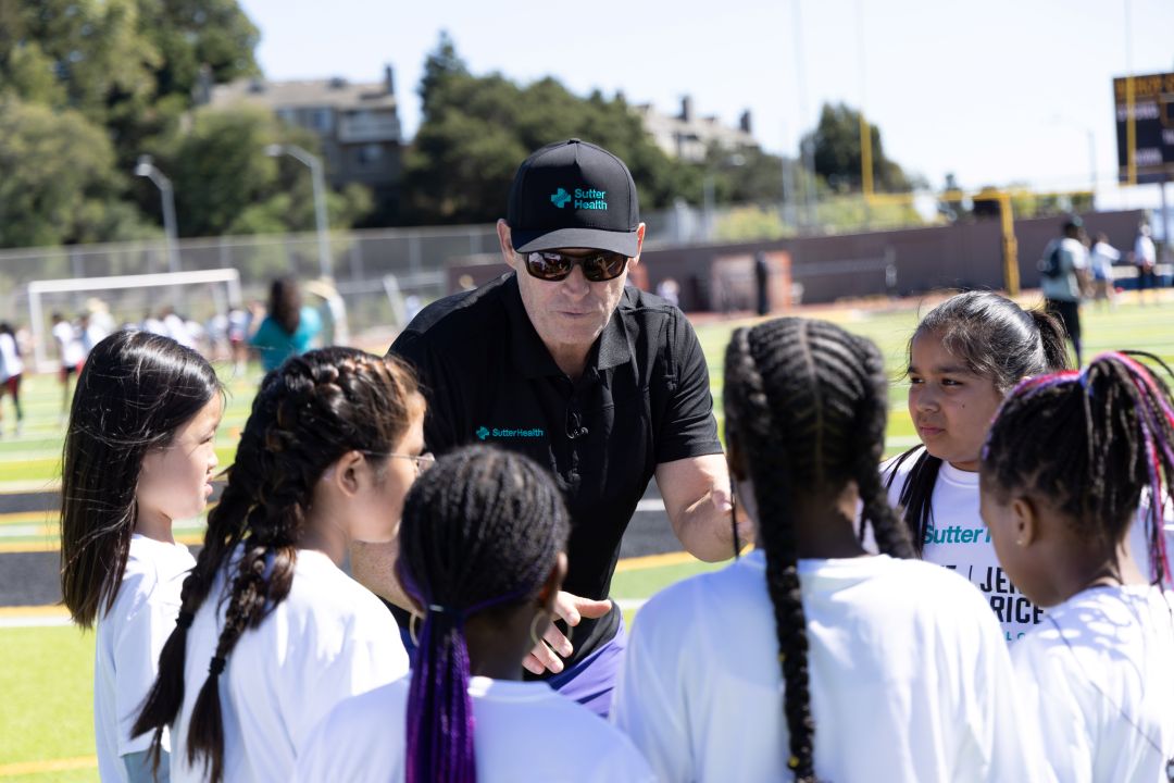 Steve Young huddles with young female athletes