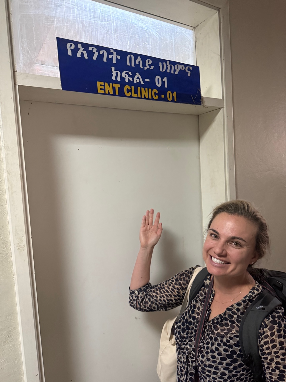A woman points to a sign on a door