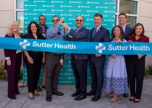 A group of people hold a Sutter Health banner at a ribbon cutting ceremony