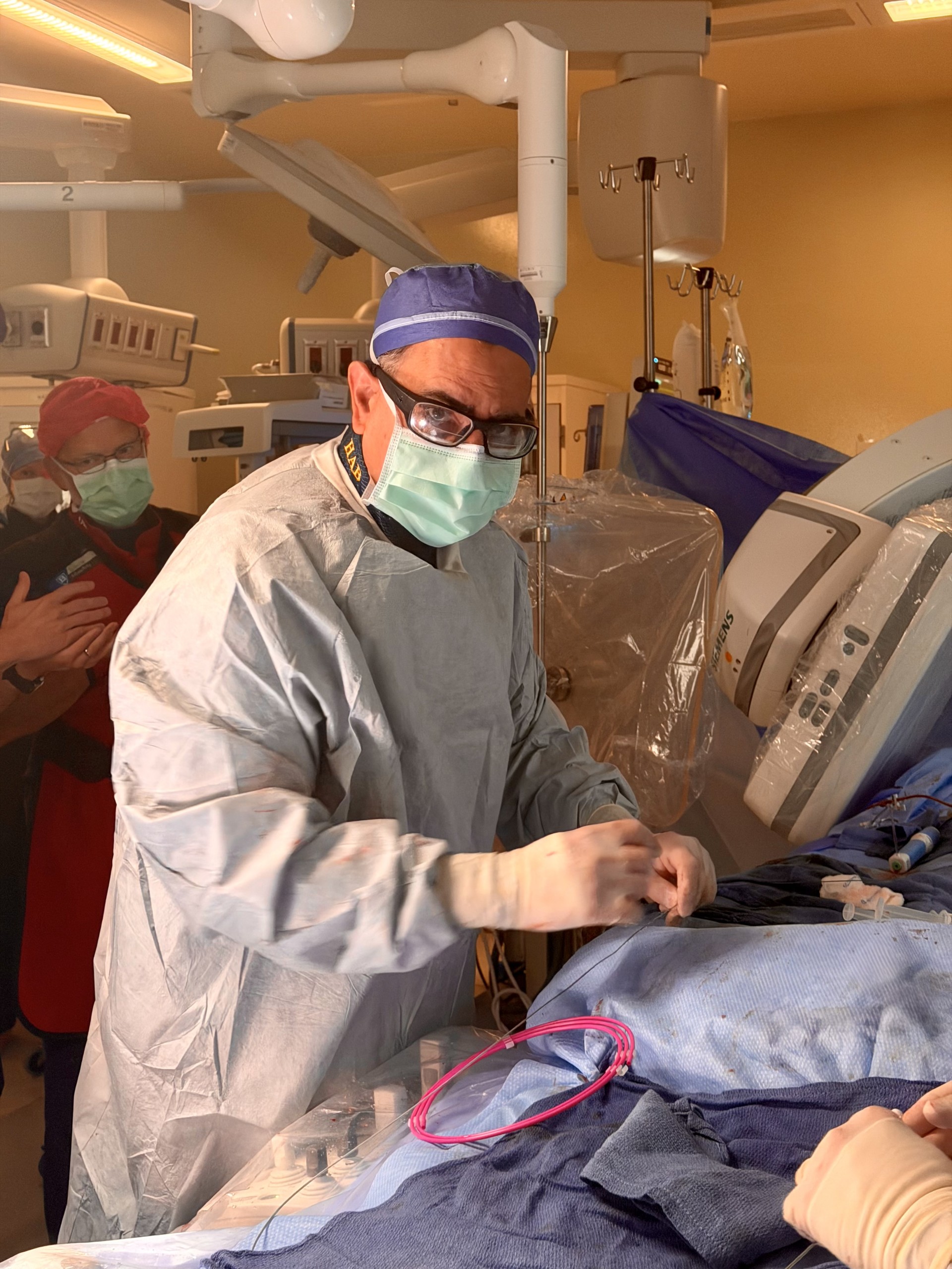A surgeon stands at the patient’s bedside in the operating room.