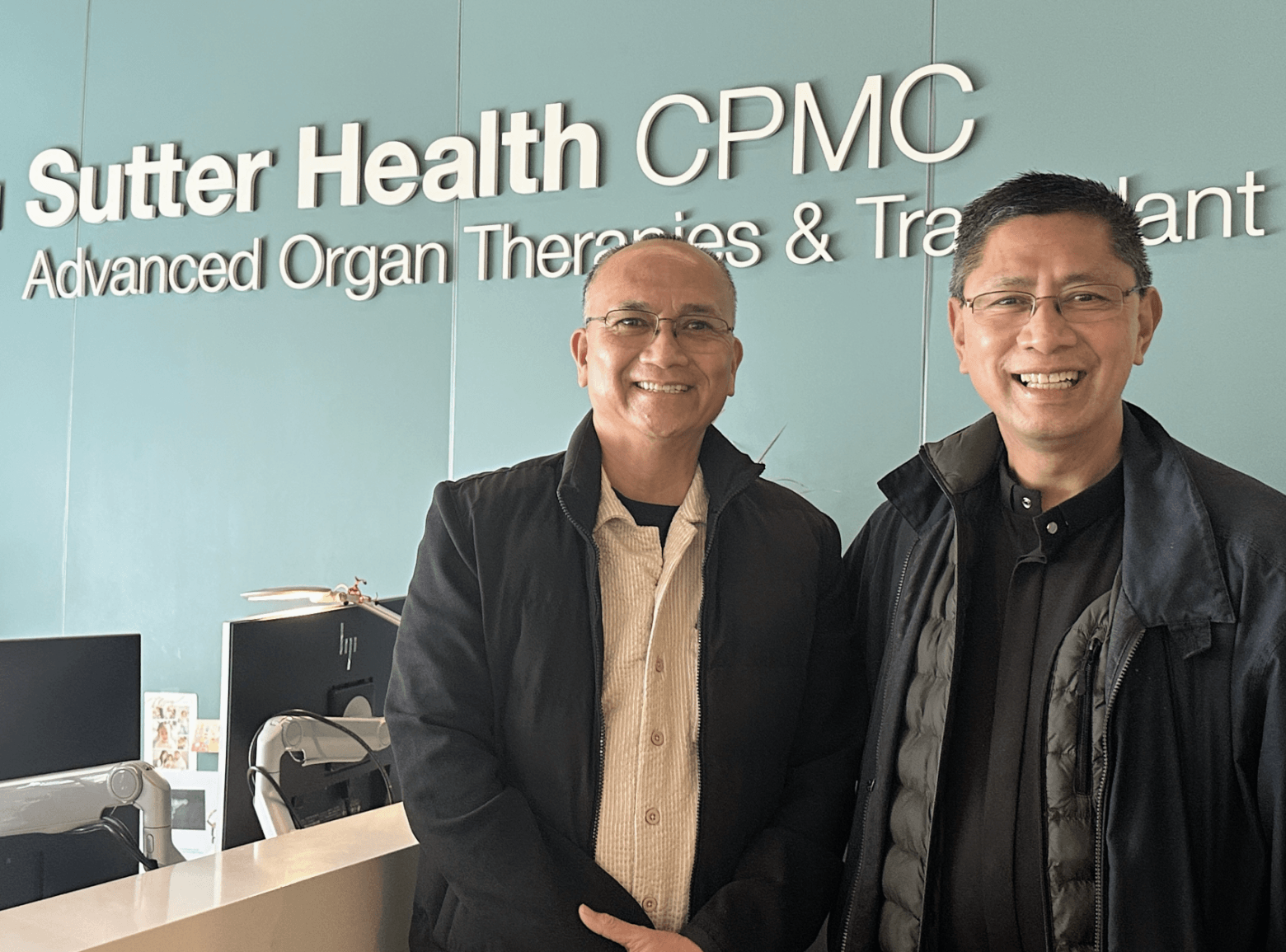 Two Filipino priests stand side by side in a medical clinic