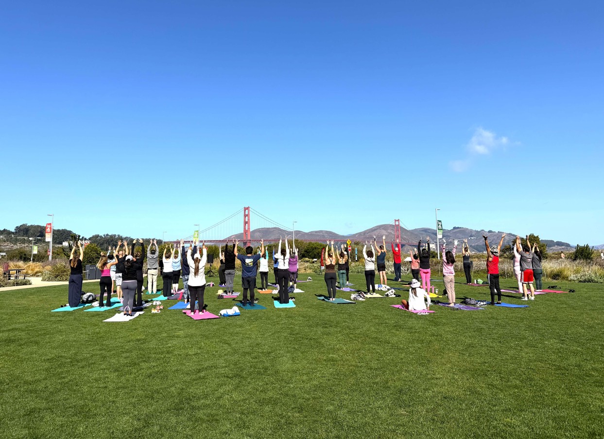 People doing yoga in the Presidio with the Golden Gate Park in the background