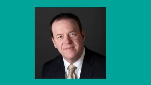 Man in suit and tie with teal border around photo