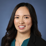 woman with dark hair and blazer, dark green shirt