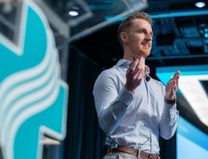 Man on stage wearing a blue button up.