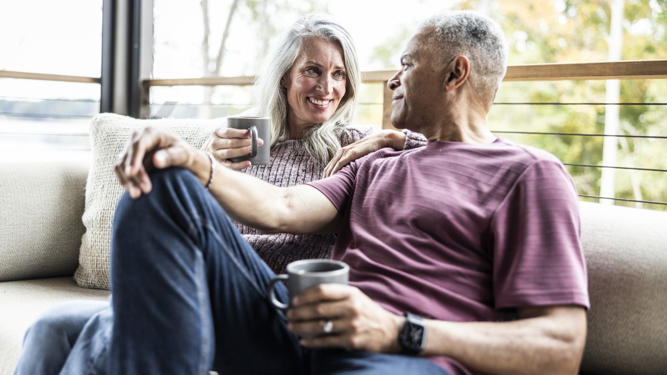 Older couple relaxing on couch with coffee cups Older couple relaxing on couch with coffee cups