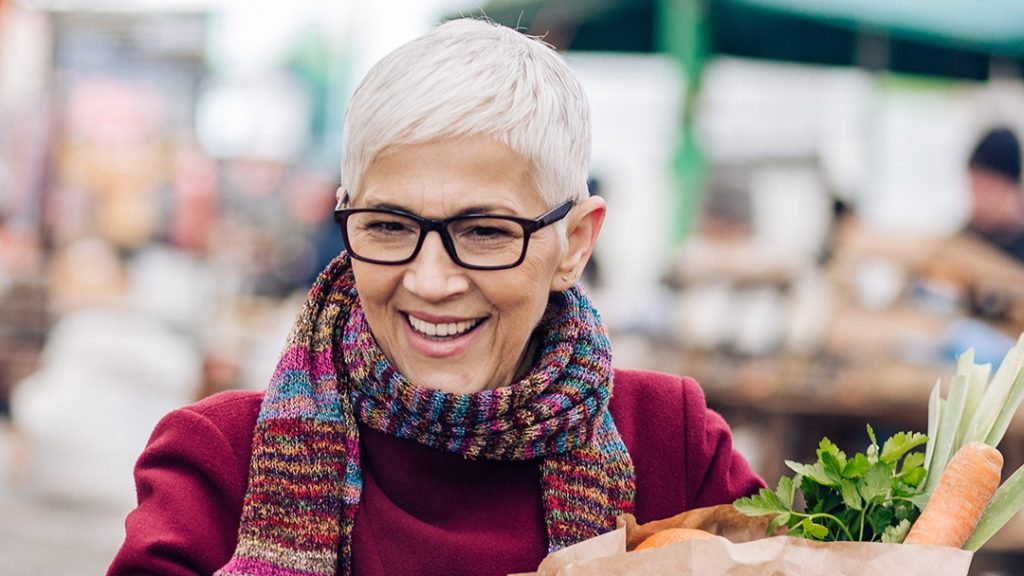 Woman with scarf and grocery bag shopping
